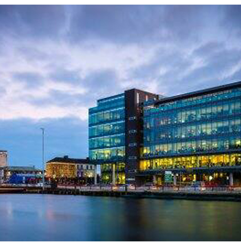 View of the commercial building at night across a water body 